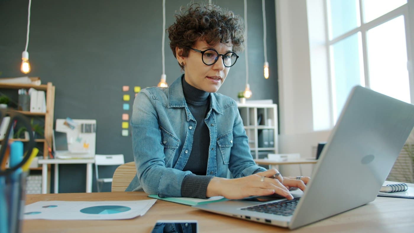 A business owner working calmly on a laptop in a bright office